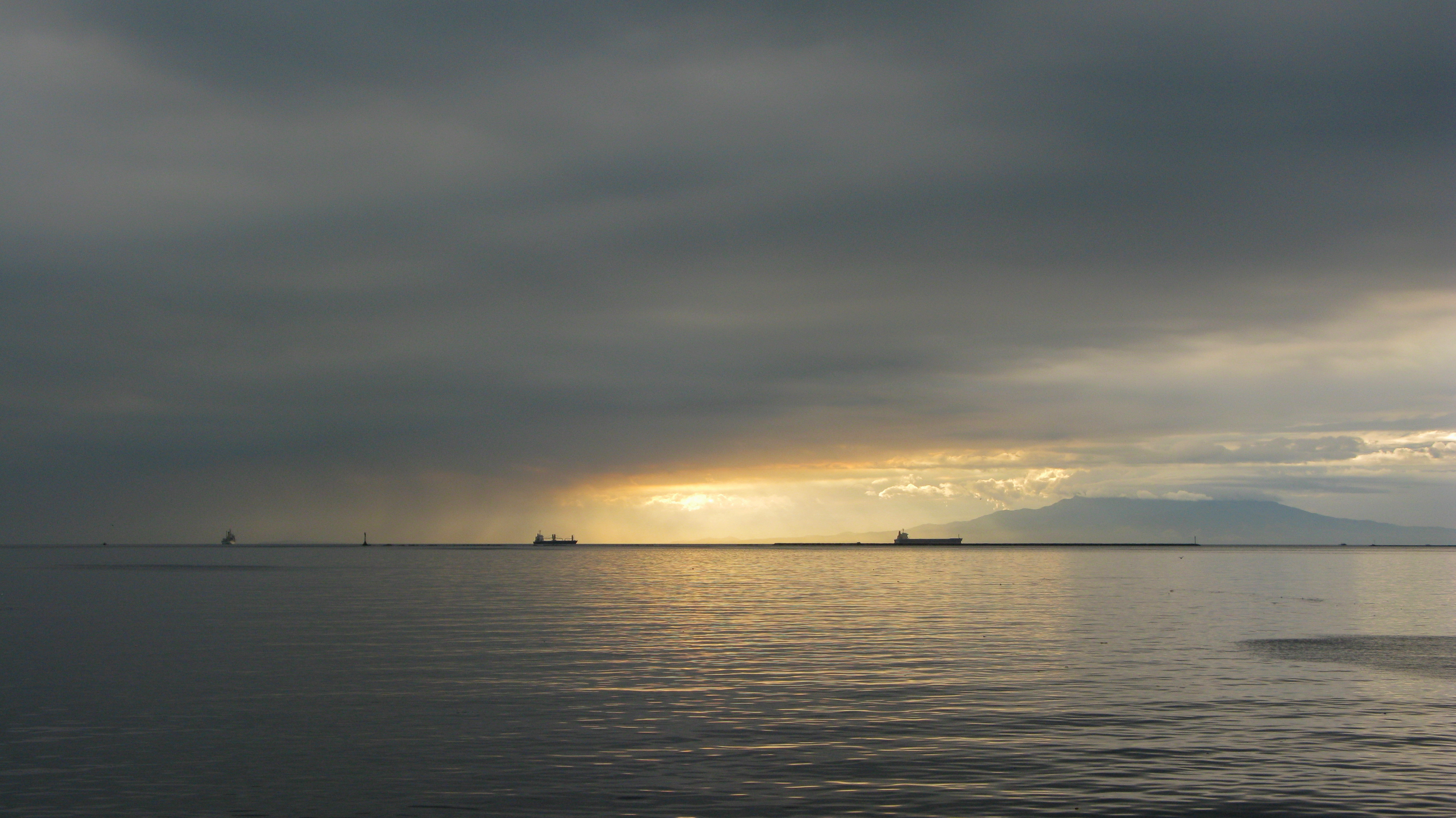 雲間の夕光が海面に反射するマニラ湾。2009年1月24日撮影の資料写真