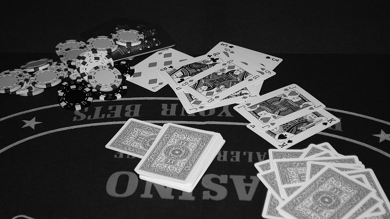 卓面に並ぶカードとポーカーチップの白黒写真